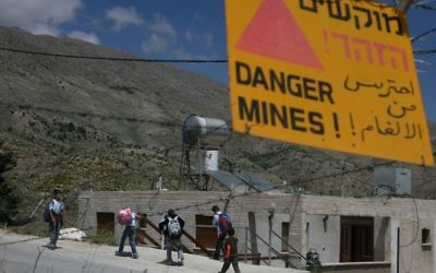 Des enfants druzes passent devant un panneau d'avertissement faisant état d'un champ de mines alors qu'ils rentrent d'une école à Majdal Shams sur le plateau du Golan (Crédit :  Lior Mizrahi / FLASH90)