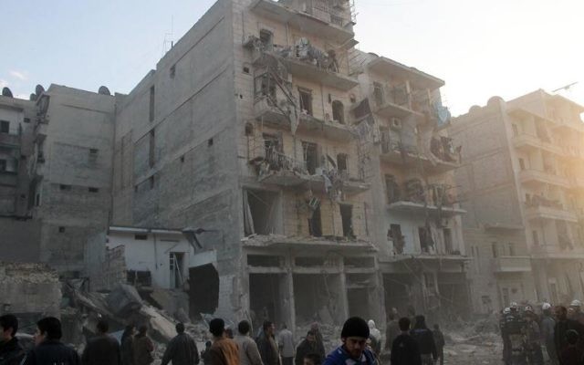 Des habitants devant un immeuble touché par une attaque aérienne de l'armée syrienne, le 29 janvier 2014 à Alep (Crédit : AFP/Mohammed Al-Khatieb)
