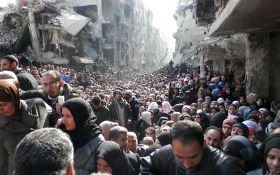La file interminable de réfugiés lors d'une distribution de nourriture organisée par l'ONU, dans les ruines du camp de réfugiés de Yarmouk, au sud de Damas (Crédit : AFP Photo/HO/UNRWA)