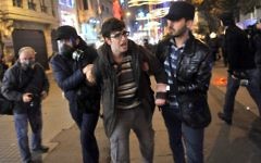 Des officiers de police en civil arrête un jeune manifestant lors des émeutes contre le nouveau projet de loi, 22 février 2014 (Crédit : AFP/Ozan Kose)