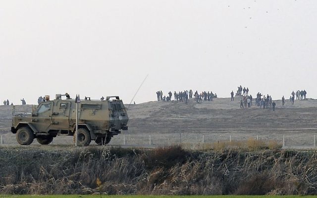 Des Palestiniens manifestent près de la barrière à la frontière entre Israël et la bande de Gaza alors qu'une jeep de l’armée israélienne patrouille à la frontière, 3 janvier 2014. (Crédit : David Buimovitch/Flash90) Des Palestiniens manifestent près de la barrière à la frontière entre Israël et la bande de Gaza alors qu'une jeep de l’armée israélienne patrouille à la frontière, 3 janvier 2014. (Crédit : David Buimovitch/Flash90)