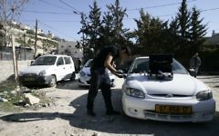 Un policier enquête sur une voiture vandalisée par le groupe "Prix à payer" dans le quartier Ein Aluza du village arabe Abu Gosh près de Jérusalem, le 10 février 2014 (Crédit : Flash90)