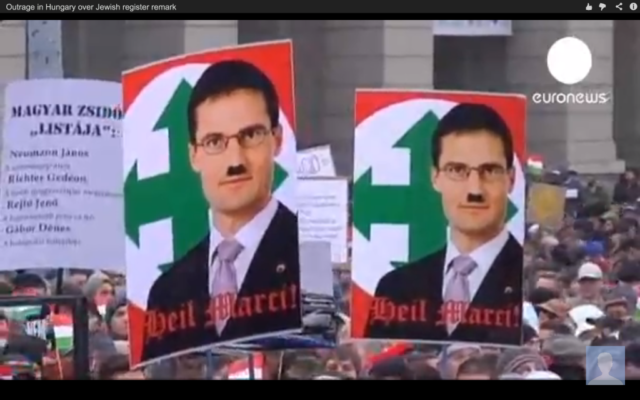 Des manifestants à Budapest brandissent des pancartes montrant le membre du parti Jobbik Marton Gyöngyosi avec la moustache d'Hitler devant l'icône du parti hongrois de la Seconde Guerre mondiale, le Parti des Croix fléchées. Un sondage récent a révélé que les juifs hongrois ont plus peur de l'antisémitisme que partout ailleurs en Europe. (Crédit : capture d'écran youtube/Euronews) Des manifestants à Budapest brandissent des pancartes montrant le membre du parti Jobbik Marton Gyöngyosi avec la moustache d'Hitler devant l'icône du parti hongrois de la Seconde Guerre mondiale, le Parti des Croix fléchées. Un sondage récent a révélé que les juifs hongrois ont plus peur de l'antisémitisme que partout ailleurs en Europe. (Crédit : capture d'écran youtube/Euronews)