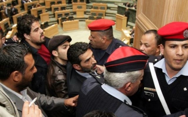 Des forces de sécurité escortent le militant qui a tenté de faire entrer le drapeau au parlement jordanien (Crédit : AFP) Des forces de sécurité escortent le militant qui a tenté de faire entrer le drapeau au parlement jordanien (Crédit : AFP)