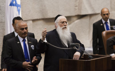 Le député Meir Porush (Yahadut Hatorah) s'est menotté au podium de la Knesset en juillet 2013 pour manifester contre le projet de loi de conscription des ultra-orthodoxes. Des centaines de milliers de haredim sont attendus lors d'une manifestation contre le projet, à Jérusalem, dimanche après-midi. (Crédit : Flash90)