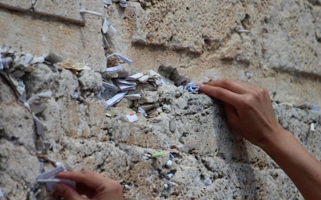 Une jeune femme insérant une prière dans le mur Occidental dans la Vieille Ville de Jérusalem (Crédit : Nechama Perton) Une jeune femme insérant une prière dans le mur Occidental dans la Vieille Ville de Jérusalem (Crédit : Nechama Perton)