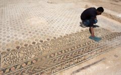 Un archéologue nettoie le sol en mosaïque qui décorait le monastère du village bédouin de Hura dans le nord du Néguev (Crédit : Menahem Kahana/AFP)