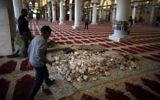 Des pierres stockées à l'intérieur de la mosquée d'Al-Aqsa, qu'un employé tente de nettoyer, en 2014. (Crédit : AFP/Ahmad Gharabli)