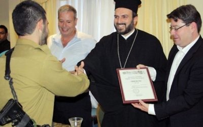 Un soldat arabe chrétien reçoit un certificat d'appréciation de la part du Père Gabriel Naddaf, à Nazareth, en 2013. (Crédit : porte-parole de l'armée israélienne)