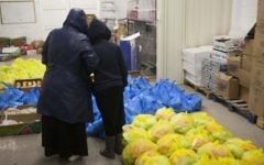 Une mère et son enfant debout devant des sacs de nourriture dans un centre pour les nécessiteux (Crédit : Yonatan Sindel/Flash 90)