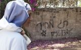 Une nonne marche le long d'un mur vandalisé par le groupe "prix à payer" (Crédit : Flash 90)
