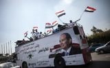 Une affiche de Sissi sur un bus rempli de supporters avec des drapeaux égyptiens en mai 2014 (Crédit : MAHMOUD KHALED/AFP)