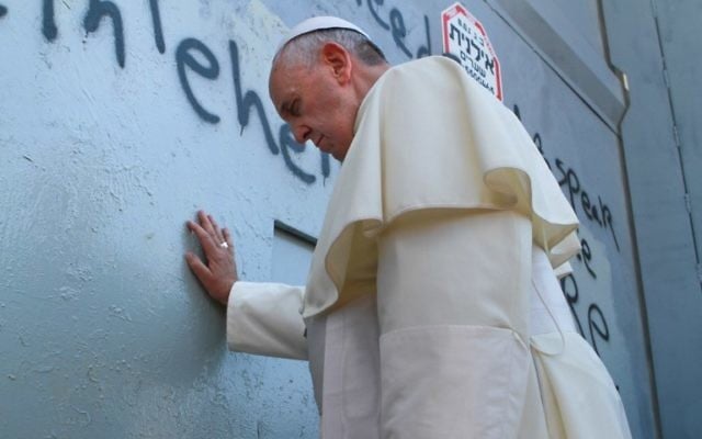 Le pape fait une prière devant la barrière de sécurité (Crédit : AFP)