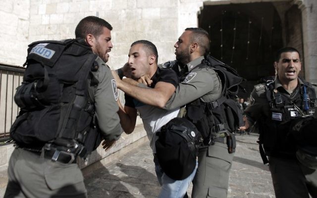Des gardes frontières détiennent un Palestinien le jour de la marche des drapeaux (Crédit : Ahmad Gharabli/AFP)
