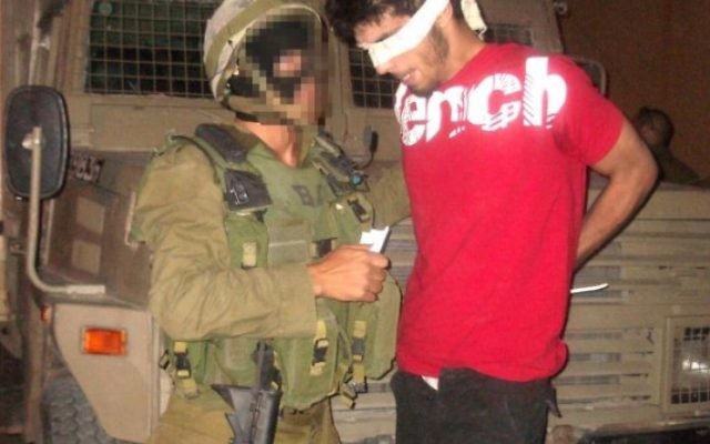 Un soldat arrête un suspect palestinien en Cisjordanie (Crédit : IDF/Flash 90)