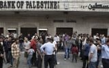Des Palestiniens devant la banque à Gaza. (Crédit : AFP/Mohammed Abed)