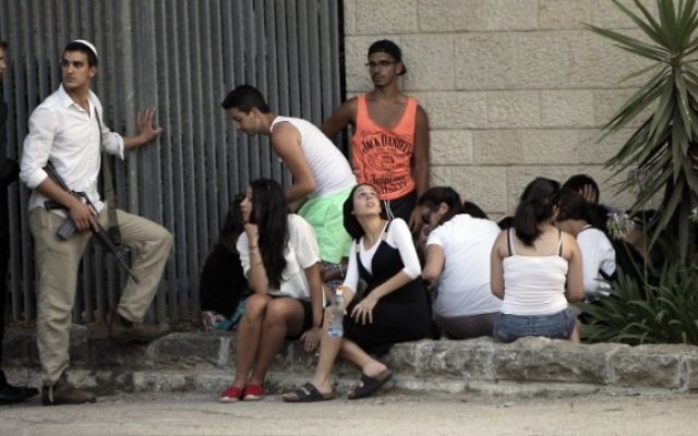 Des Israéliens à l'abri lors d'une sirène retentissant près de Jérusalem (Crédit : AFP: Ahmad Gharabli) Des Israéliens à l'abri lors d'une sirène retentissant près de Jérusalem (Crédit : AFP: Ahmad Gharabli)