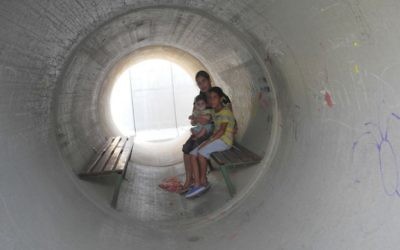Une famille israélienne se réfugie dans un abri anti-bombes fait d'une canalisation en béton aménagée pendant la guerre de Gaza en 2014. (Melanie Lidman/Times of Israel)