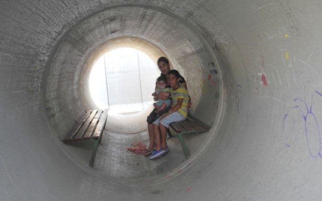 Une famille israélienne se réfugie dans un abri anti-bombes fait d'une canalisation en béton aménagée pendant la guerre de Gaza en 2014. (Melanie Lidman/Times of Israel)