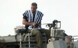 Un soldat israélien priant sur un char de l'armée (Crédit : David Buimovitch/Flash90)