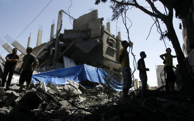 Palestiniens marchant parmi les décombres d'une maison détruite suite à un tir de missile israélien, à Rafah le 14 juillet, 2014 (Crédit : Abed Rahim Khatib/Flash90)