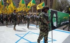 Photo d'illustration: Des terroristes du Kataeb Hezbollah tiennent les drapeaux jaunes de la branche irakienne du groupe chiite et un portrait de guide spirituel de l'Iran, l'ayatollah Ruhollah Khomeini, et marchent sur ​​un drapeau israélien peint sur ​​le sol pendant la journée d'al-Qods (Jérusalem), à Bagdad, le 25 Juillet 2014. (Crédit : AFP / Ali Al-Saadi)