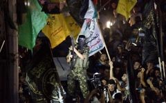 Un militant brandit son arme alors qu'il tire des coups de feu en l'air après avoir rejoint des centaines d'habitants de Gaza, le 26 août 2014 pour célébrer un accord de cessez-le-feu conclu entre Israël et le Hamas. (Crédit : AFP PHOTO / ROBERTO SCHMIDT)