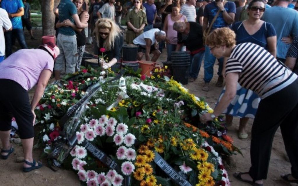 Des Israéliens déposent des couronnes de fleurs sur la tombe de Shahar Melamed, 43 ans, qui a été tué la veille par un tir de mortier palestinien dans le kibboutz Nirim près de la frontière d'Israël avec la bande de Gaza, le 27 août 2014 (Crédit : AFP / MENAHEM KAHANA)