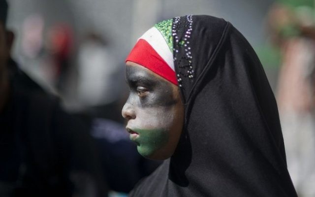 Une jeune fille portant un hijab, avec son visage peint aux couleurs du drapeau palestinien, participe à une marche anti-Israël au Cap, en Afrique du Sud le samedi 9 août, 2014 (Crédit : Roger Bosch / AFP)