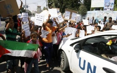 Des enfants palestiniens manifestent devant une école de l'UNRWA (Crédit : Flash 90)