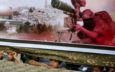 Des enfants palestiniens regardent de derrière une banderole lors d'un rassemblement pro-Hamas à Rafah, au sud de la bande de Gaza, le 17 Août 2014 (Crédit : Abed Rahim Khatib / Flash90)