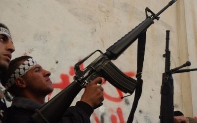 Un Palestinien masqué des Brigades des martyrs d'al-Aqsa, une branche armée du mouvement Fatah du président de l'AP Mahmoud Abbas, détient une arme tout en parlant aux médias à Balata  - camp de réfugiés près de Naplouse, février 2008 (Crédit : Wagdi ASHTIYEH / Flash90 )