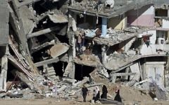 Une famille passe devant les ruines d'immeubles à Shejaiya, dans la bande de Gaza, le 27 août 2014. (Crédit : AFP/Roberto Schmidt)
