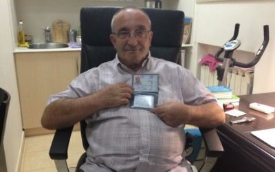 Yaakov Weksler-Waszkinel montre sa nouvelle carte d'identité israélienne à son domicile à Jérusalem. (Crédit : Renée Ghert-Zand / The Times of Israel)