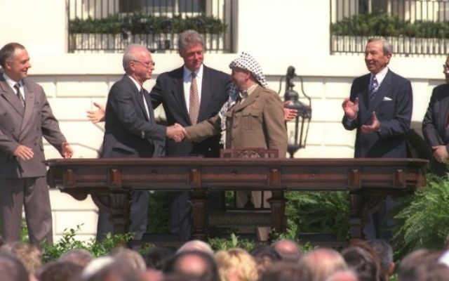 Bill Clinton regarde Yitzhak Rabin et Yasser Arafat se serrer la main lors de la signature historique des accords d'Oslo, le 13 septembre 1993. (Crédit : courtoisie GPO) Bill Clinton regarde Yitzhak Rabin et Yasser Arafat se serrer la main lors de la signature historique des accords d'Oslo, le 13 septembre 1993. (Crédit : courtoisie GPO)