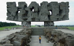 Mémorial à la "porte d'entrée" du camp. Le Pylône symbolique censé représenter les corps mutilés et se lit comme un signe yiddish abstrait (Crédit : domaine public)