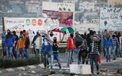 Des jeunes arabes en train de brandir le drapeau palestinien et de jeter des pierres vers la police des frontières à l'entrée du village arabe de Kafr Kanna, le 8 novembre 2014. (Crédit photo : Hadas Parush / Flash90)