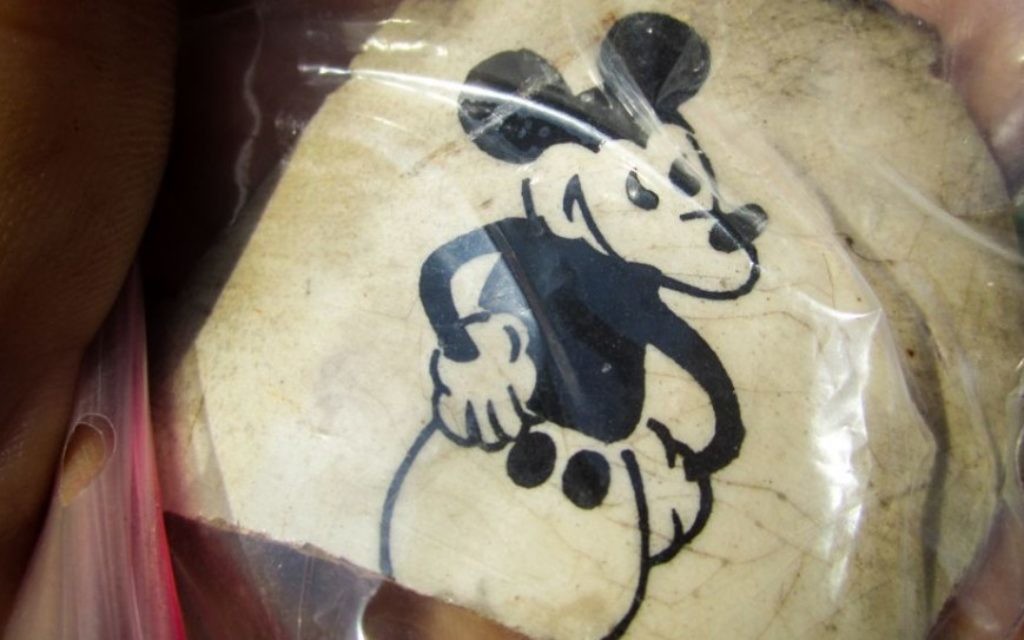 Un fragment d'une tasse en céramique excavé à l'ancien camp d'extermination nazi de Sobibor, en Pologne orientale, imprimé avec un dessin animé de Mickey Mouse est vu. L'artefact a été déterré par des archéologues Wojtek Mazurek et Yoram Haimi il y a plusieurs mois, et photographié le 11 novembre 2014, en dehors de Sobibor (Crédit: Matt Lebovic / The Times of Israel) Un fragment d'une tasse en céramique excavé à l'ancien camp d'extermination nazi de Sobibor, en Pologne orientale, imprimé avec un dessin animé de Mickey Mouse est vu. L'artefact a été déterré par des archéologues Wojtek Mazurek et Yoram Haimi il y a plusieurs mois, et photographié le 11 novembre 2014, en dehors de Sobibor (Crédit: Matt Lebovic / The Times of Israel)