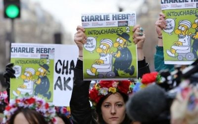 Des militantes Femen arborant les Une de Charlie Hebdo pendant la Marche républicaine le 11 janvier 2015 sur la Place de la République (Crédit: AFP/LOIC VENANCE)