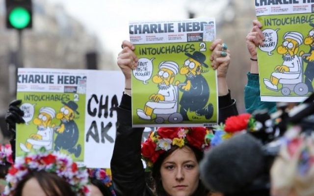 Des militantes Femen arborant les Une de Charlie Hebdo pendant la Marche républicaine le 11 janvier 2015 sur la Place de la République (Crédit: AFP/LOIC VENANCE)