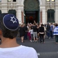 Illustration: Un homme avec une kippa regarde les gens prendre part à une manifestation organisée par le CRIF devant la synagogue de Lyon, le 31 Juillet 2014. (Crédit : Romain Lafabregue/AFP)