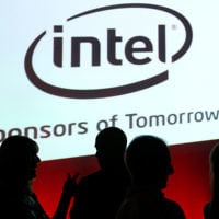 Des Israéliens devant le logo de la société Intel (Crédit : Moshe Shai/Flash90)