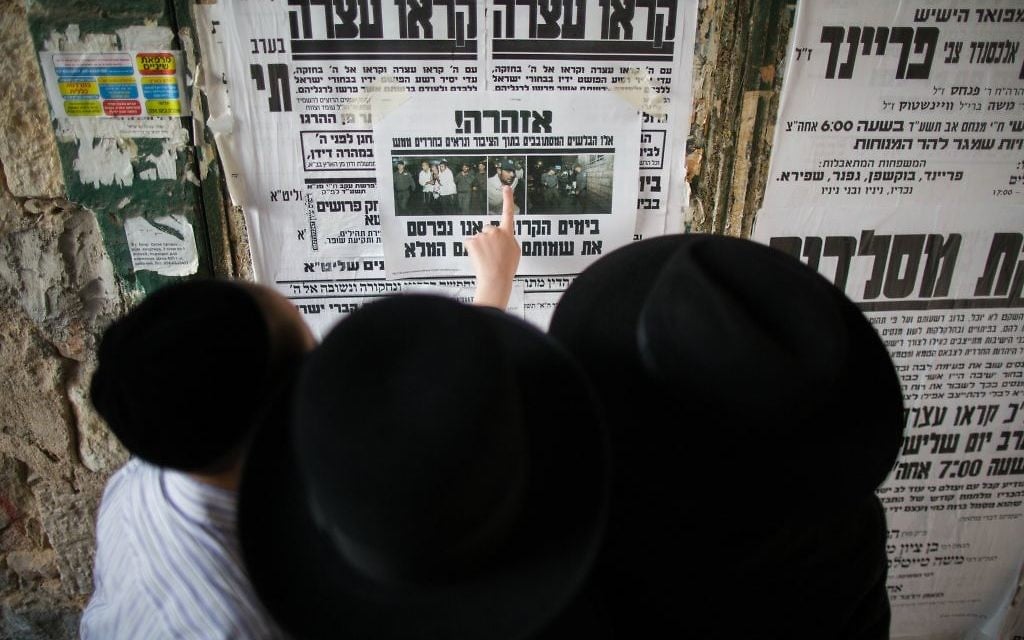 Des Juifs ultra-orthodoxes lisent le journal dans une rue du quartier de Mea Shearim (Crédit : Yonathan Sindel/Flash 90) Des Juifs ultra-orthodoxes lisent le journal dans une rue du quartier de Mea Shearim (Crédit : Yonathan Sindel/Flash 90)