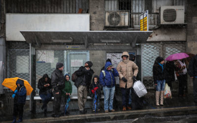 Israéliens vu attendant à un arrêt de bus dans le centre de Jérusalem tandis que la neige commence à tomber sur le premier jour de l'hiver. Le 7 janvier 2015. (Crédit : Hadas Parush / FLASH90)