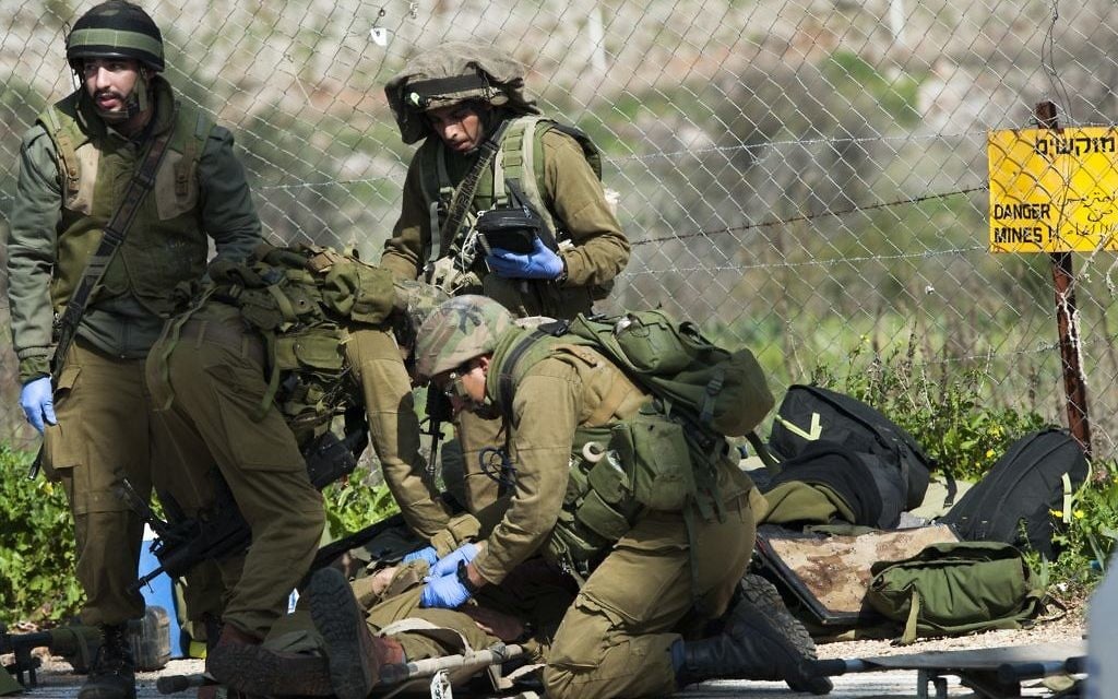 Des troupes soignent un soldat blessé après qu'un véhicule militaire ait été sous le feu le long de la frontière israélienne avec le Liban le 28 janvier, 2015. (Crédit : Basal Awidat / Flash90) Des troupes soignent un soldat blessé après qu'un véhicule militaire ait été sous le feu le long de la frontière israélienne avec le Liban le 28 janvier, 2015. (Crédit : Basal Awidat / Flash90)