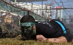 Un jeune Palestinien rampe sous un obstacle de barbelés lors d'une cérémonie de remise de diplôme pour un camp d'entraînement dirigé par le Hamas le 29 janvier 2015, à Khan Younis, dans le sud de la bande de Gaza. (Crédit : AFP / SAID KHATIB)