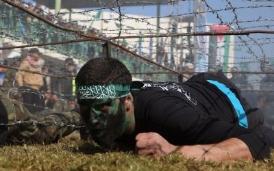 Un jeune Palestinien rampe sous un obstacle de barbelés lors d'une cérémonie de remise de diplôme pour un camp d'entraînement dirigé par le Hamas le 29 janvier 2015, à Khan Younis, dans le sud de la bande de Gaza. (Crédit : AFP / SAID KHATIB)