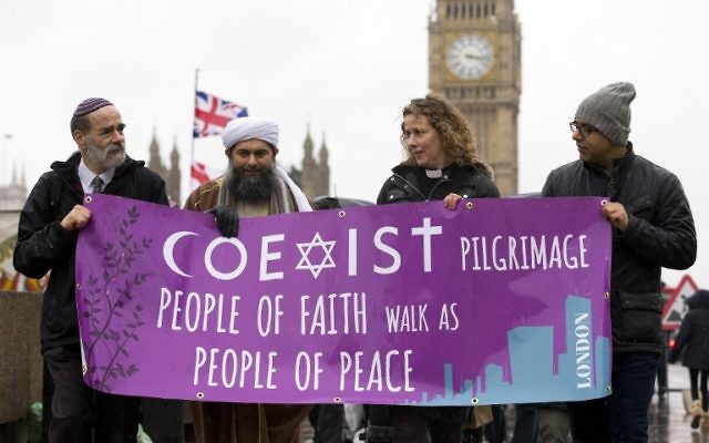 De gauche à droite : Rabbi Jonathan Wittenberg, l'Assistant du secrétaire général de l' Association musulmane de Grande Bretagne, Ibrahim Mogra, la réverende Margaret Cave et une personne non identifiée portant la bannière COEXIST alors qu'il traverse le pont de Westminster pendant la marche inter-religieuse le 19 février 2015 (Crédit : AFP PHOTO / JUSTIN TALLIS ) De gauche à droite : Rabbi Jonathan Wittenberg, l'Assistant du secrétaire général de l' Association musulmane de Grande Bretagne, Ibrahim Mogra, la réverende Margaret Cave et une personne non identifiée portant la bannière COEXIST alors qu'il traverse le pont de Westminster pendant la marche inter-religieuse le 19 février 2015 (Crédit : AFP PHOTO / JUSTIN TALLIS )