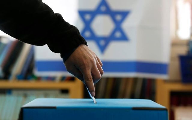 Un israélien met son bulletin dans l’urne (Crédit : Flash90)