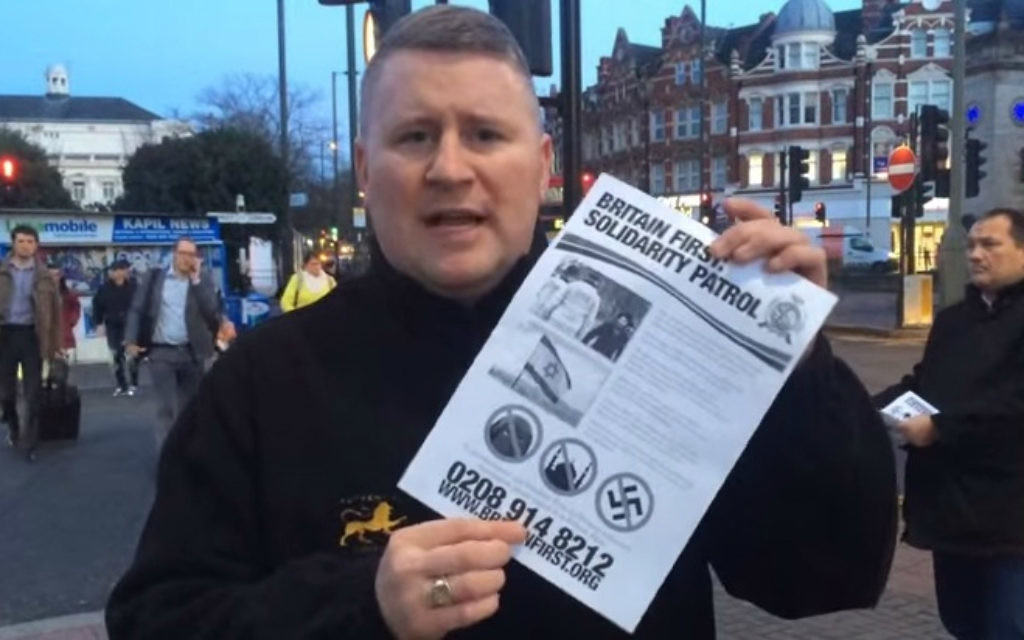 Le dirigeant de Britain First tenant une affiche pour la "patrouille de solidarité" dans un quartier juif de Londres en janvier 2015 (Crédit : Capture d'écran YouTube) Le dirigeant de Britain First tenant une affiche pour la "patrouille de solidarité" dans un quartier juif de Londres en janvier 2015 (Crédit : Capture d'écran YouTube)